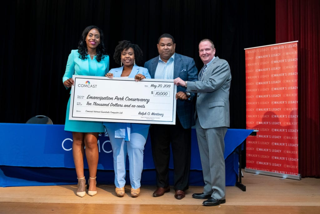 Four people onstage at the Women of Color in Tech event hold an oversized check made out to the Emancipation Park Conservancy