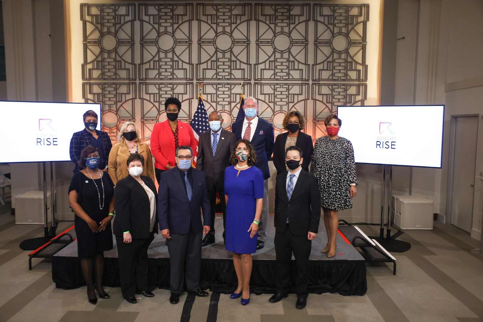 A group of ten people standing in front of a stage at a Comcast RISE event.