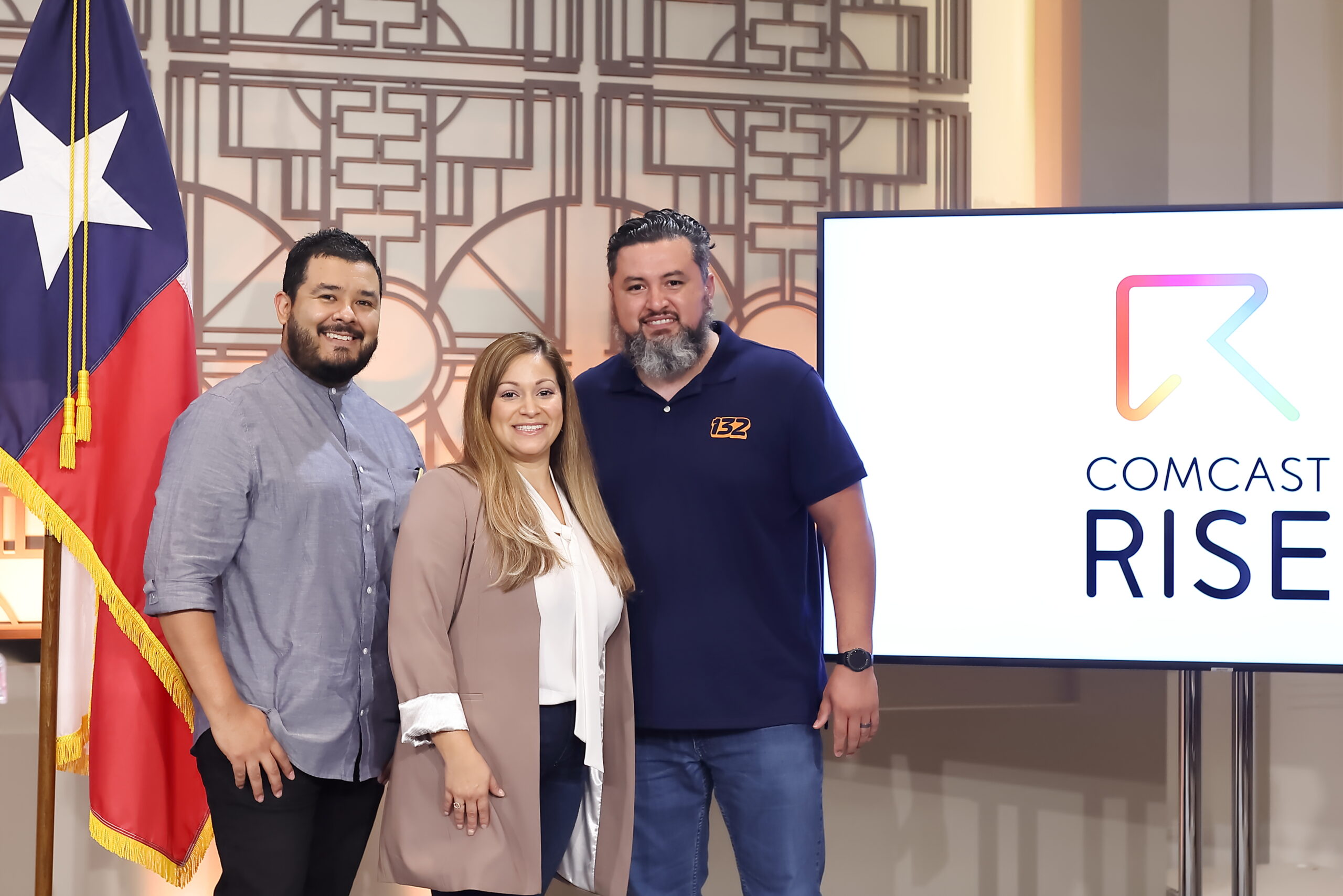 Three Houston locals smiling in front of a Comcast RISE logo displayed on a large screen.