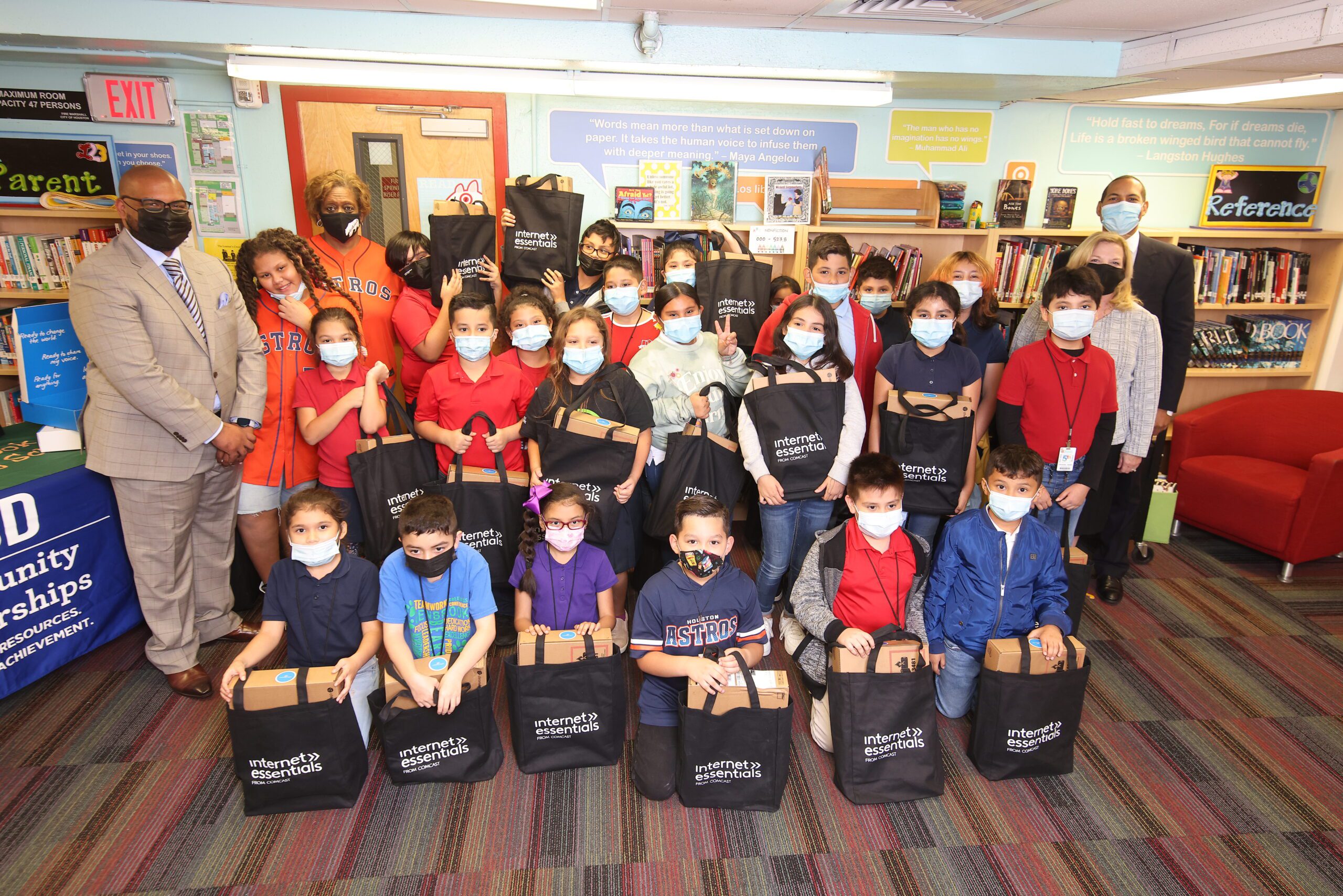 A classroom full of young students holding free laptops during an Internet Essentials event.