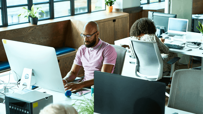 Colleagues using desktop computers in a coworking spaces.