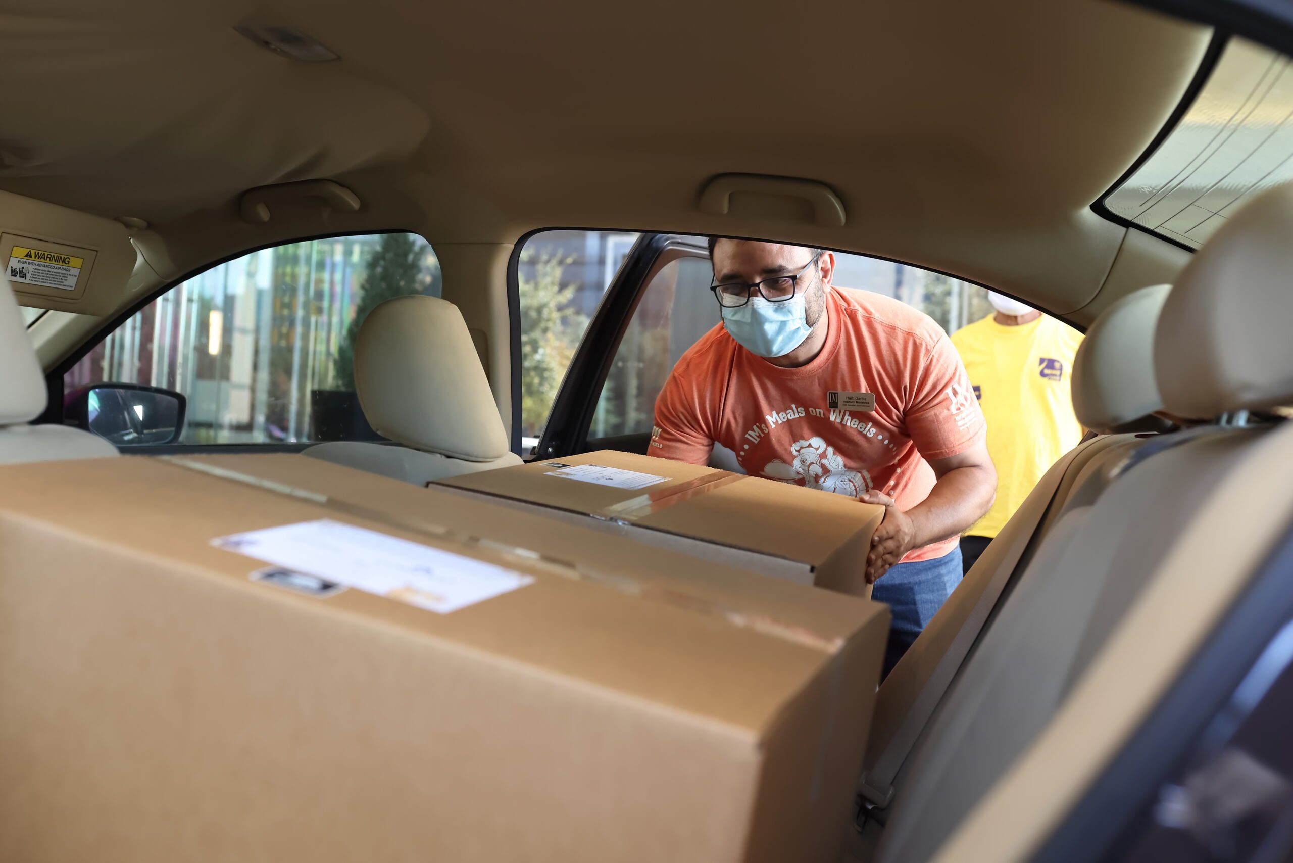 A Interfaith Ministries for Greater Houston volunteer examining boxes of supplied loaded into a car.