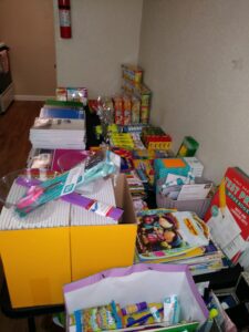 Many boxes and bags of school supplies lining a wall in a room