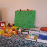 A table with patterned tablecloth holding various school supplies