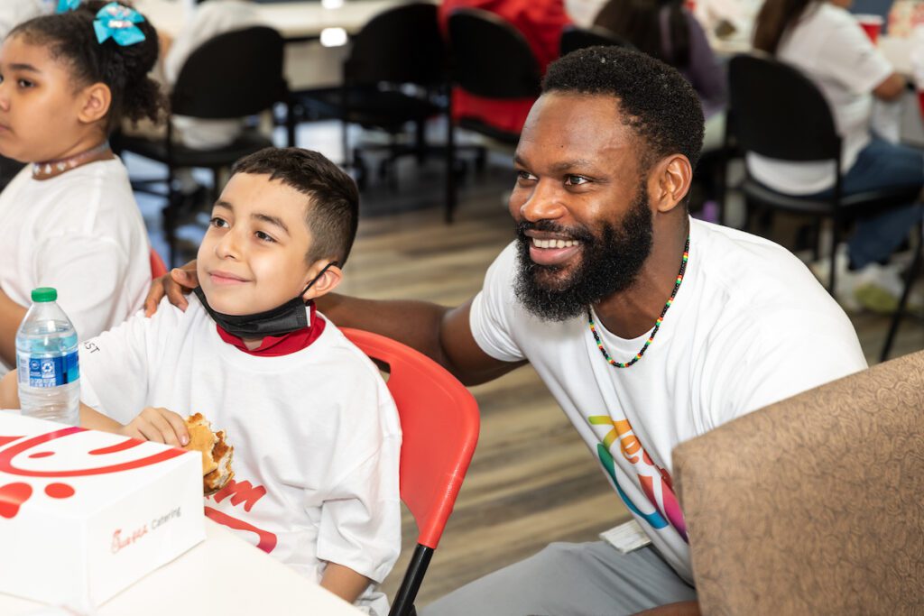 Man leaning down near young boy eating sandwich