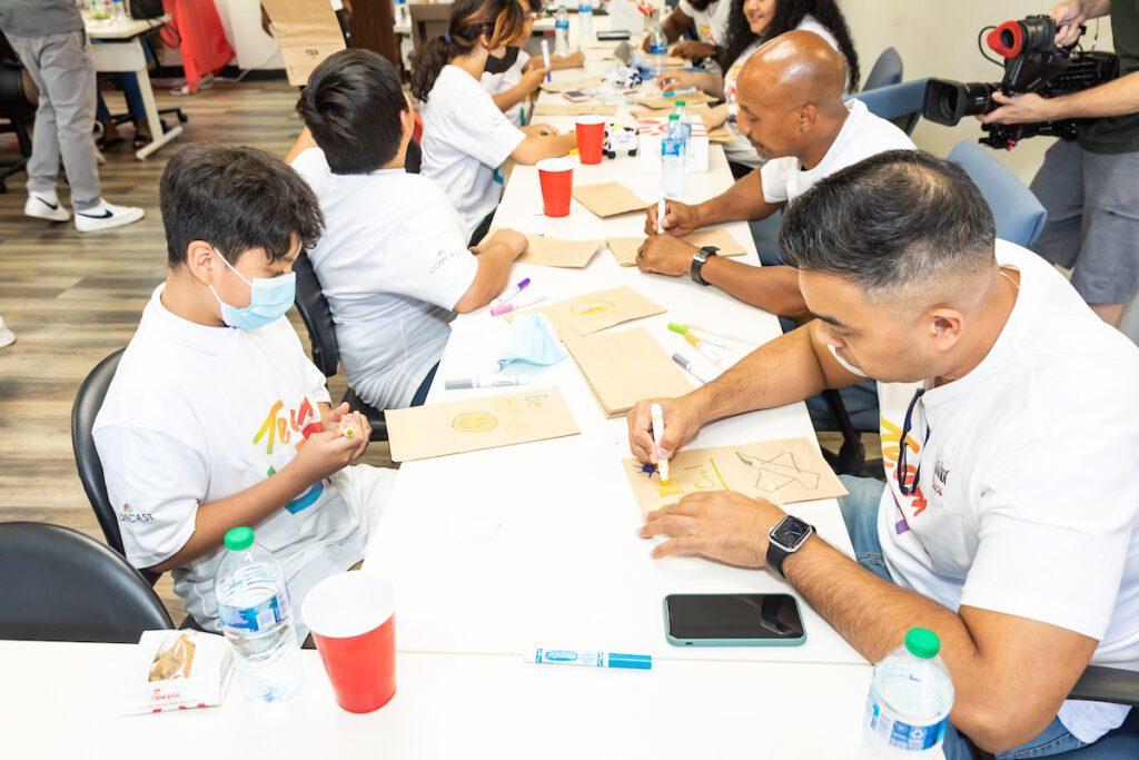 Group of people at long table decorating paper lunch bags