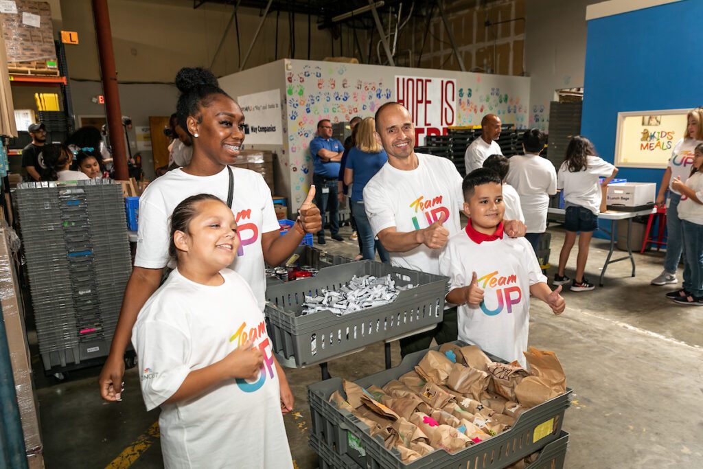 Four people standing next to bins with big smiles and thumbs up