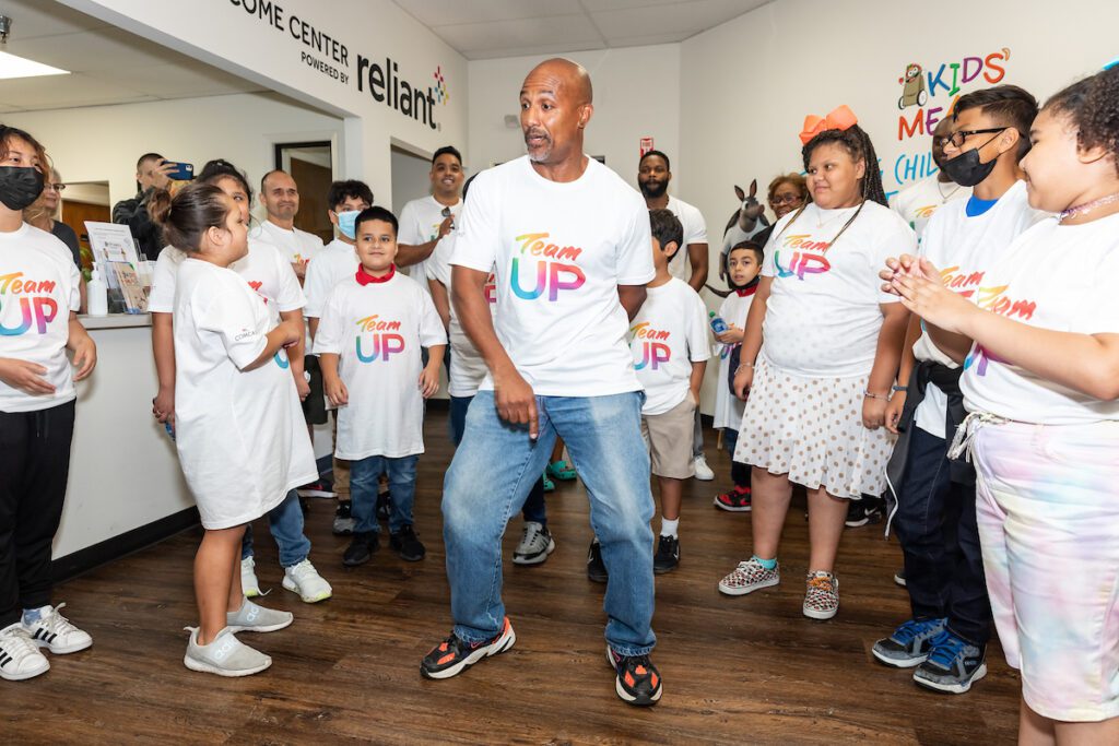 Gentleman dancing in center of group of volunteers and kids