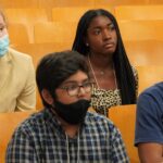 Four students seated and looking up at speaker