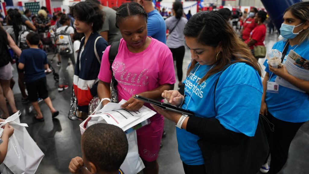 Volunteer showing attendee something on a tablet