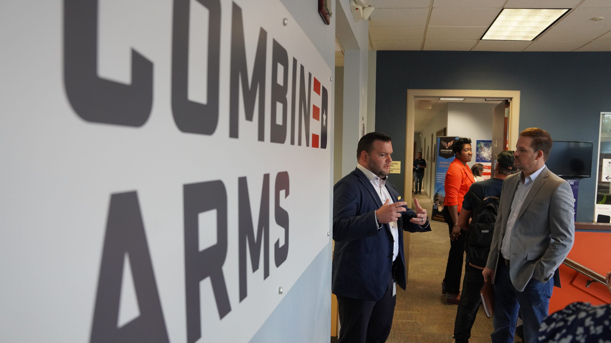 Combined Arms sign on wall with people speaking in the distance