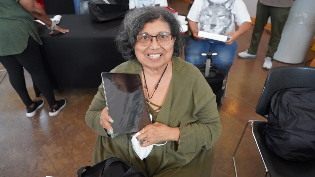 Seated woman holding up tablet.