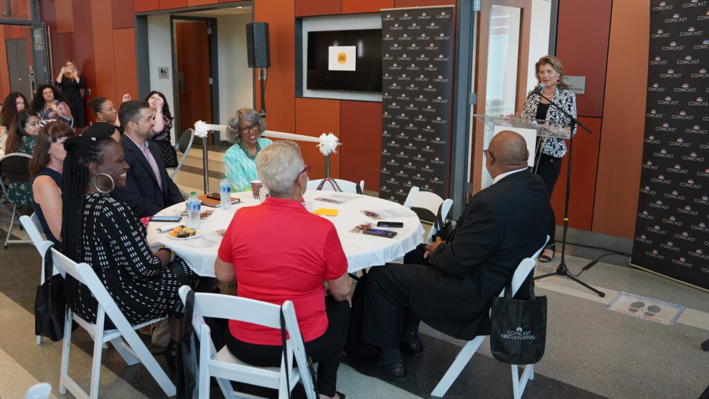 Guests seated at round tables looking toward a speaker