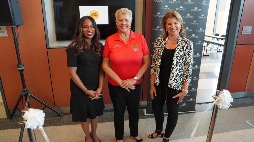 Three women standing together and smiling as they pose for a picture