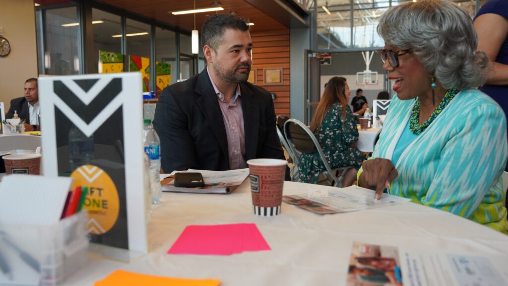 A man and woman sitting at a table and speaking with each other