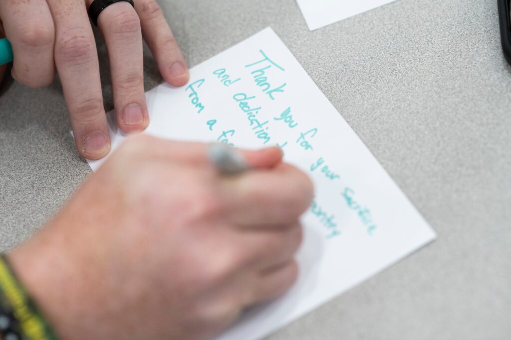 Close up on hand writing thank you note in green marker