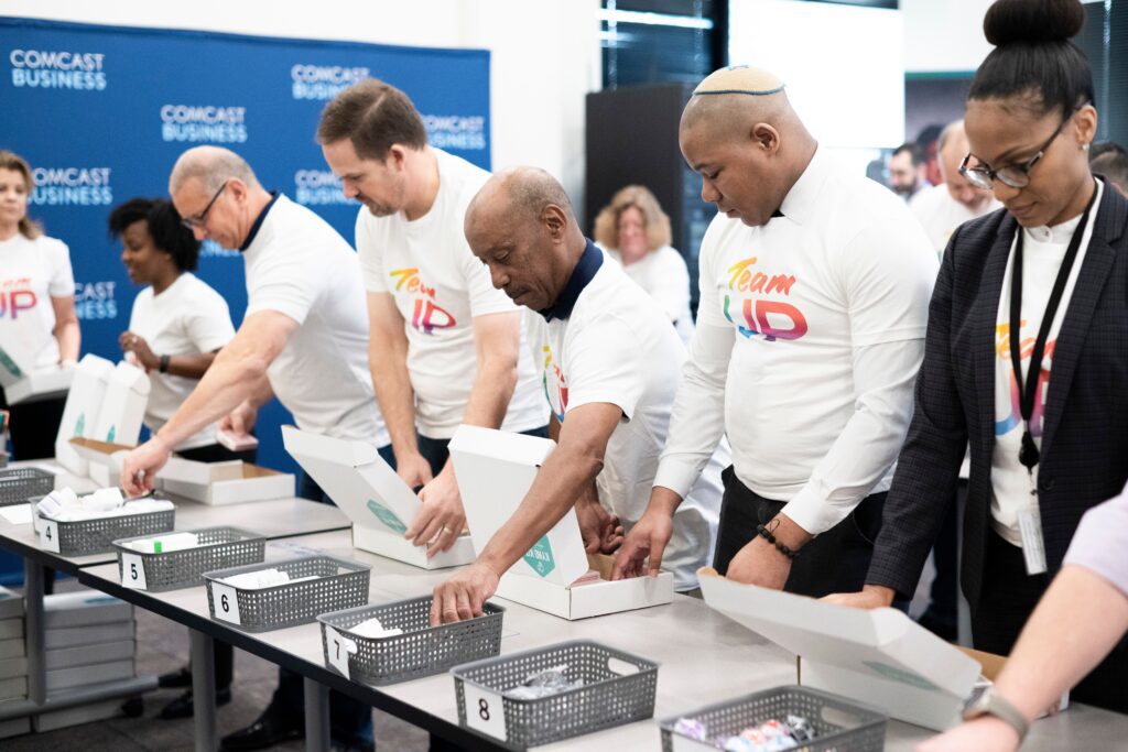 Group of volunteers bend over table adding items to boxes