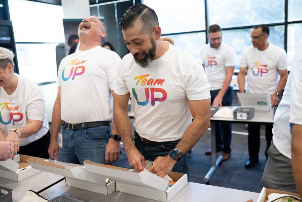 Two men laughing and working together adding items to small boxes