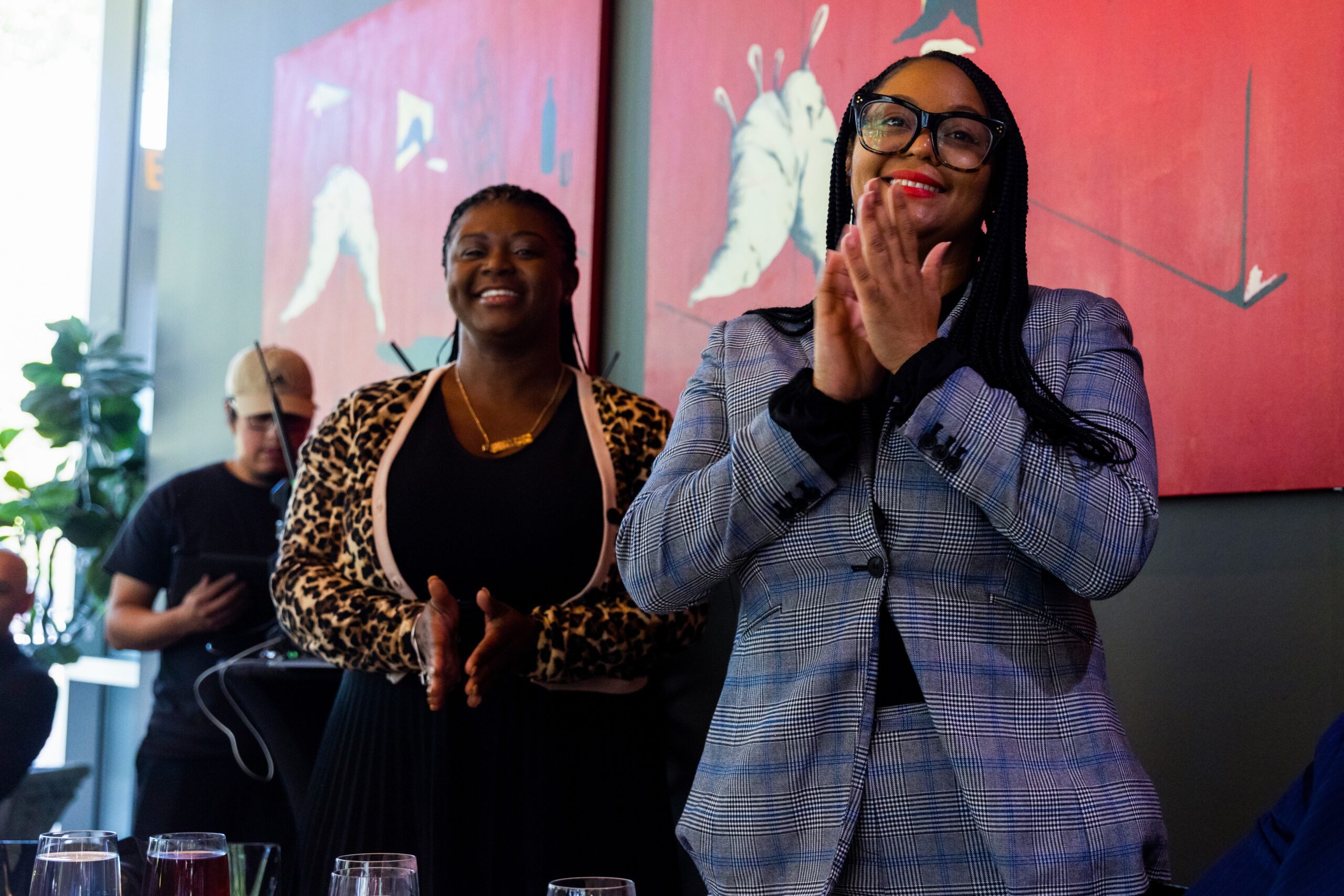 Two women standing with smiling faces and clapping