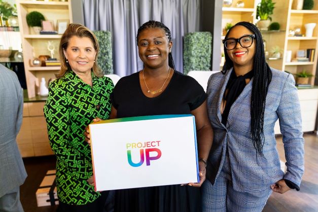 Three women posing holding Project Up sign