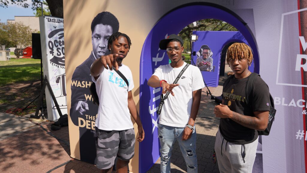 Three young men posing in front of arched sign