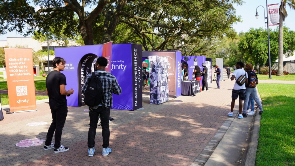 Image taken from a distance of students walking around Xfininty signs