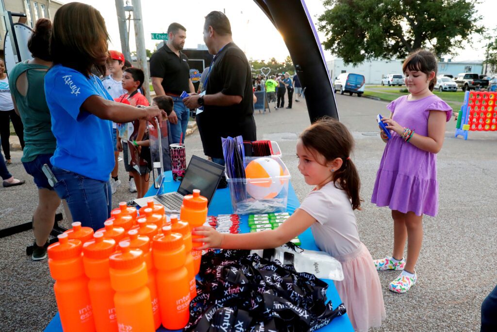 Two young girls taking Xfinity logo gifts from table