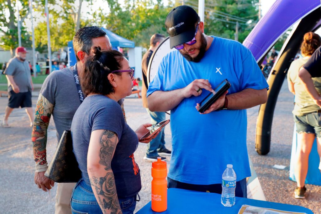 Man wearing blue Xfinity t-shirt showing couple information on a tablet