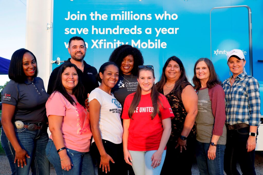 Group of people smiling and posing for a picture in front of Xfinity Mobile sign