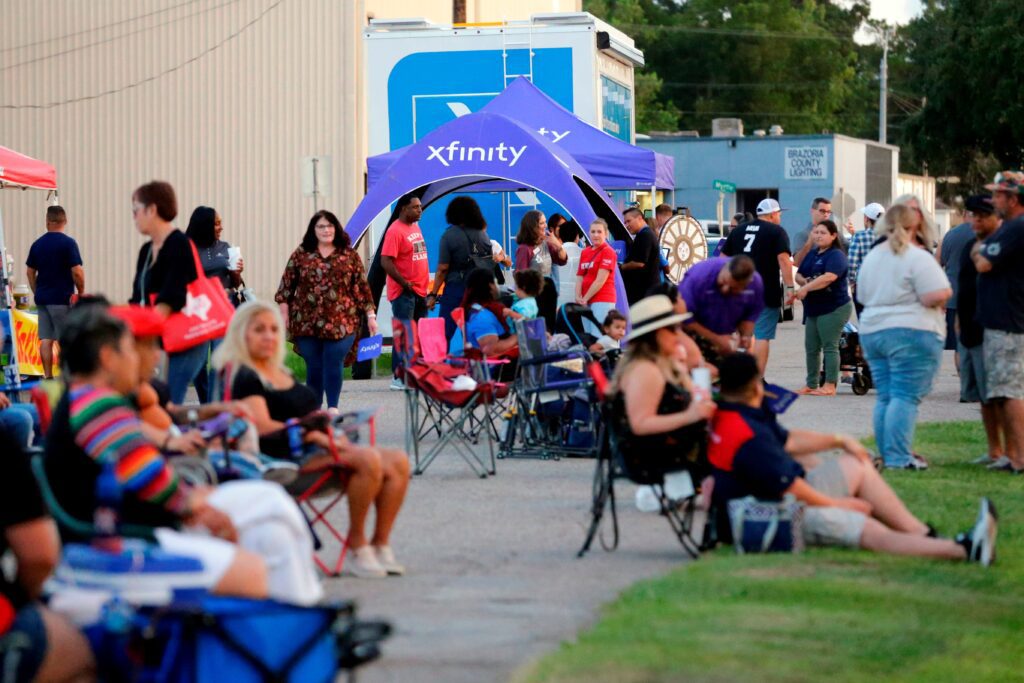 Xfinity tent in distance with many people sitting in lawn chairs