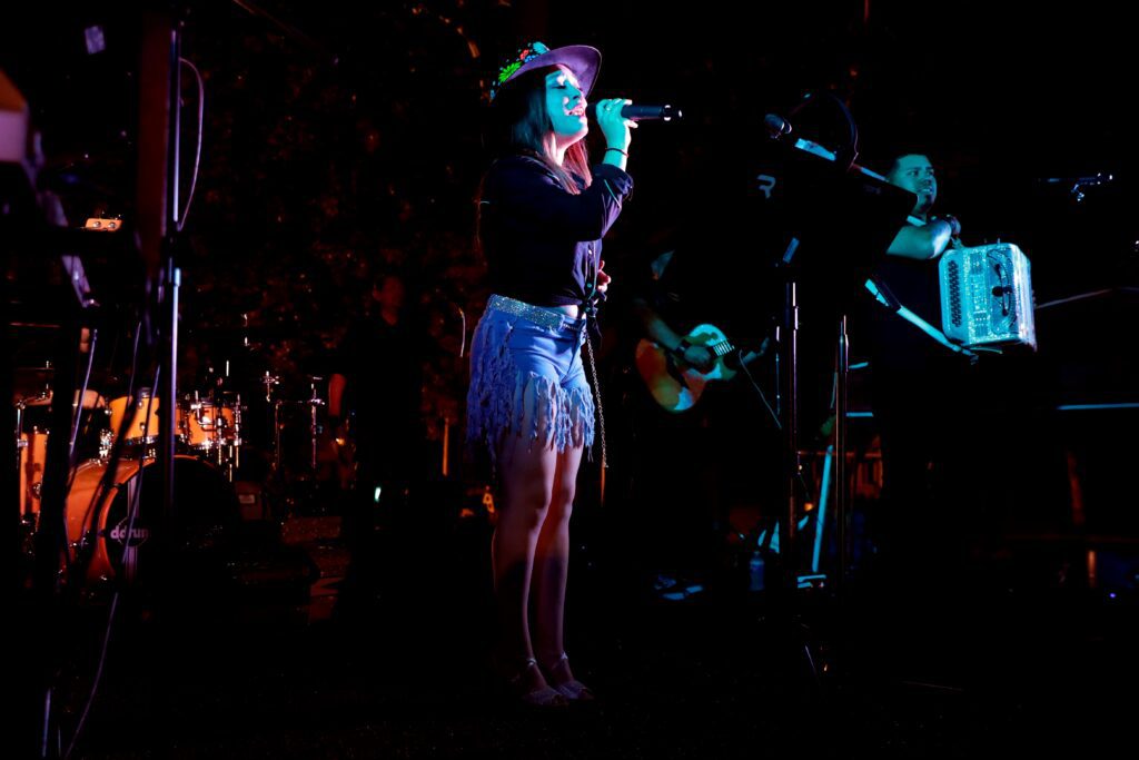 Woman holding a micorphone and singing on stage.