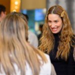 Smiling woman with wavy hair looking at another woman