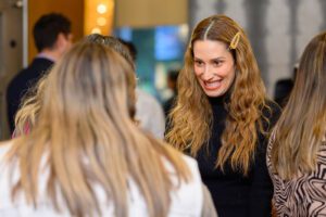 Smiling woman with wavy hair looking at another woman