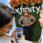 Woman with hands on hips posing for picot in front of a floral decorated Xfinity wall