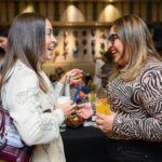 Two women smiling and chatting holding beverages