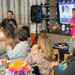 Chef Hugo Ortega speaking into microphone to group of people seated at tables