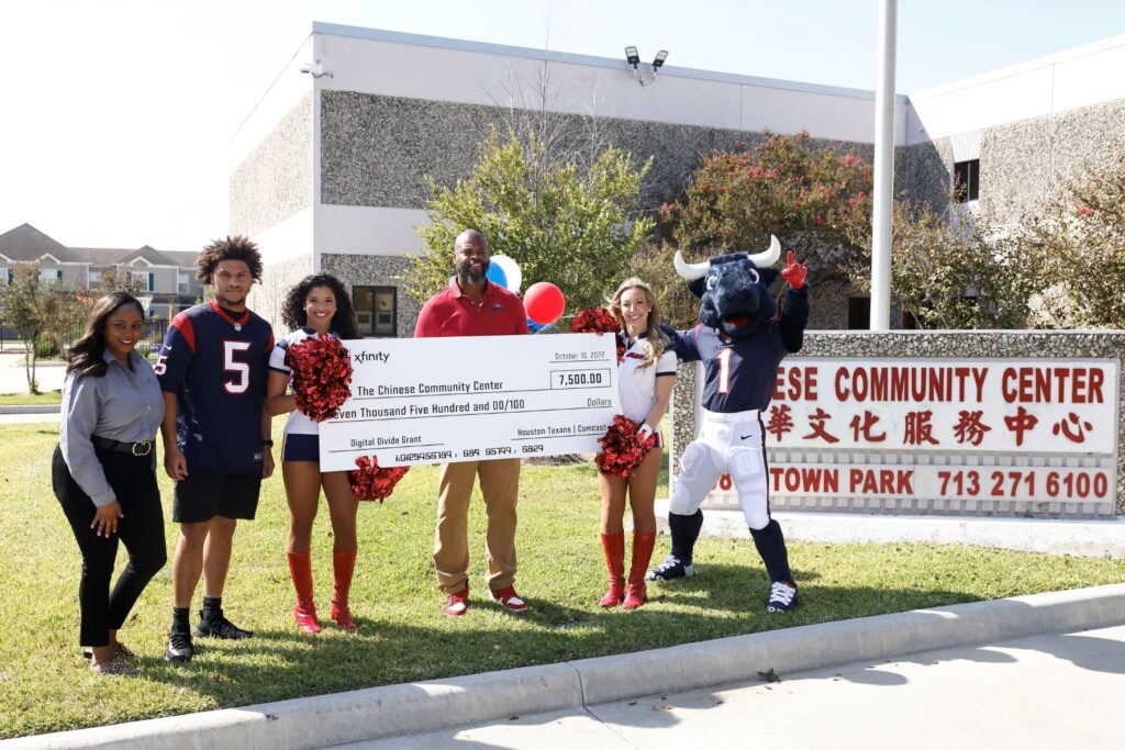 Group of people standing outside community center holding a large check