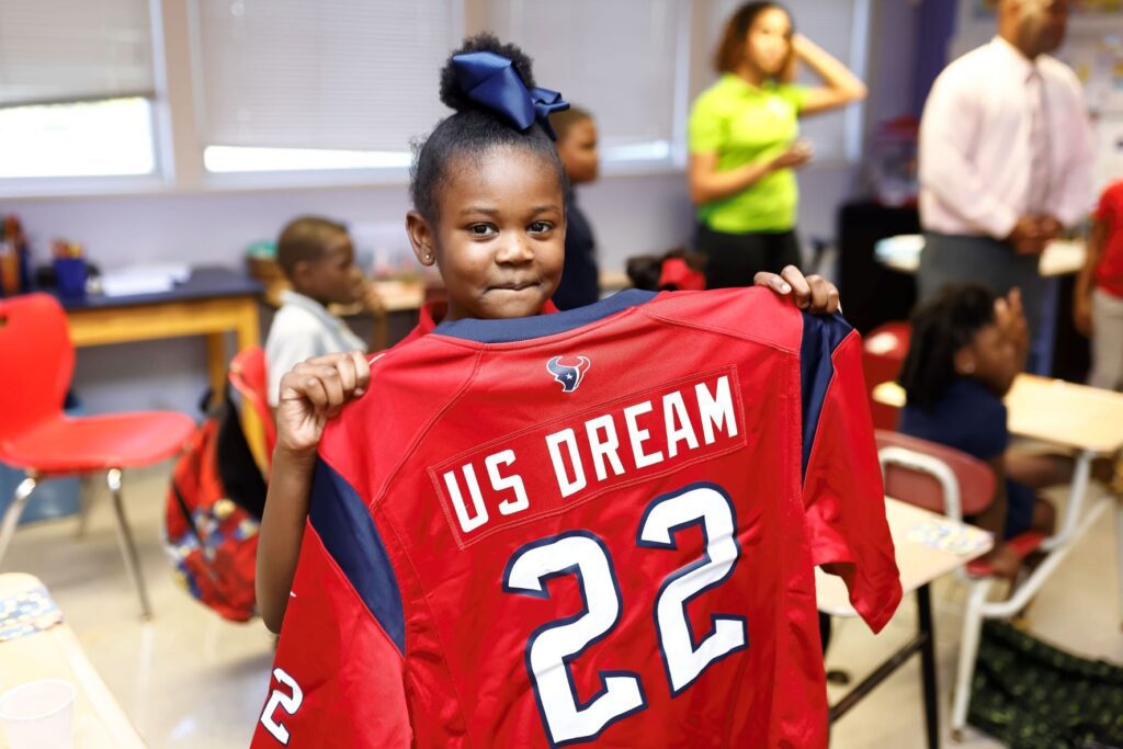 Young girl posing for picture holding red jersey 