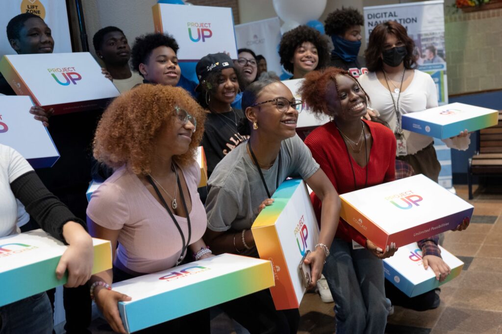 Young adults and children posing for picture holding Team Up boxes.