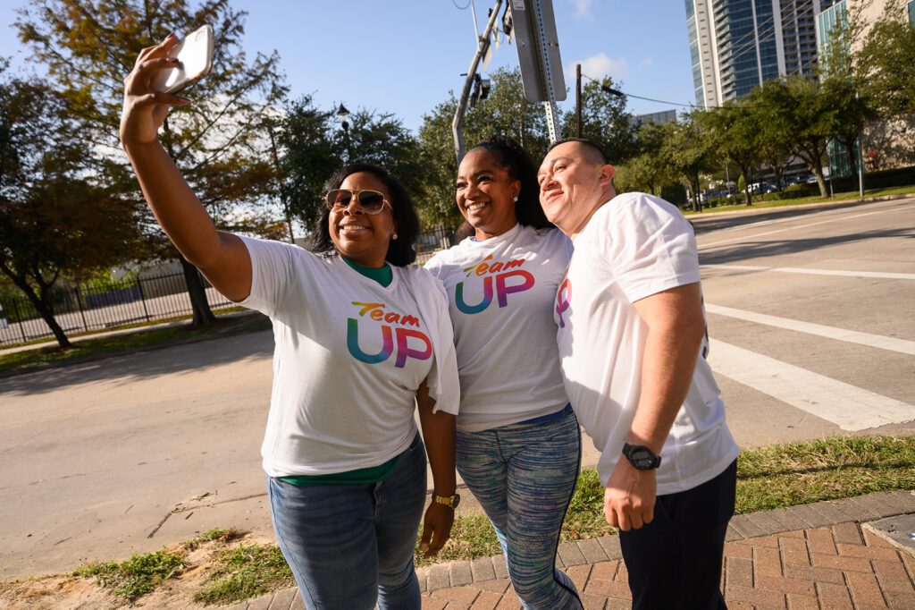 Three Team Up volunteers emailing and posing for a selfie