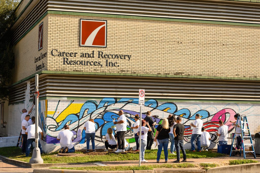 Volunteers working with paint to add color to various parts of mural