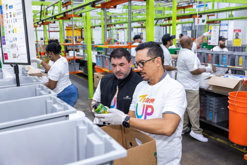 Two Team Up volunteers adding vitamin bottles to bins at Houston food bank.