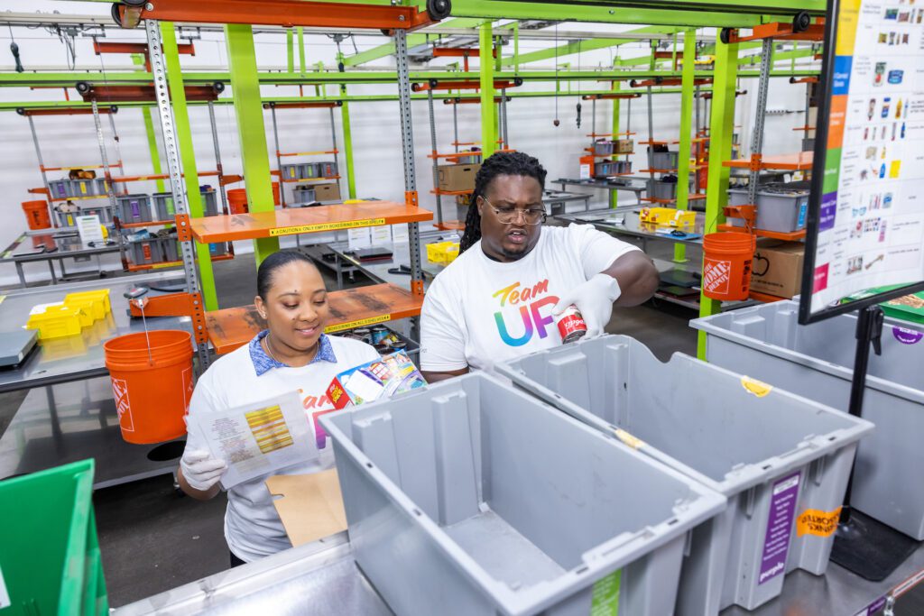 Two Team Up volunteers filling bins at food bank.