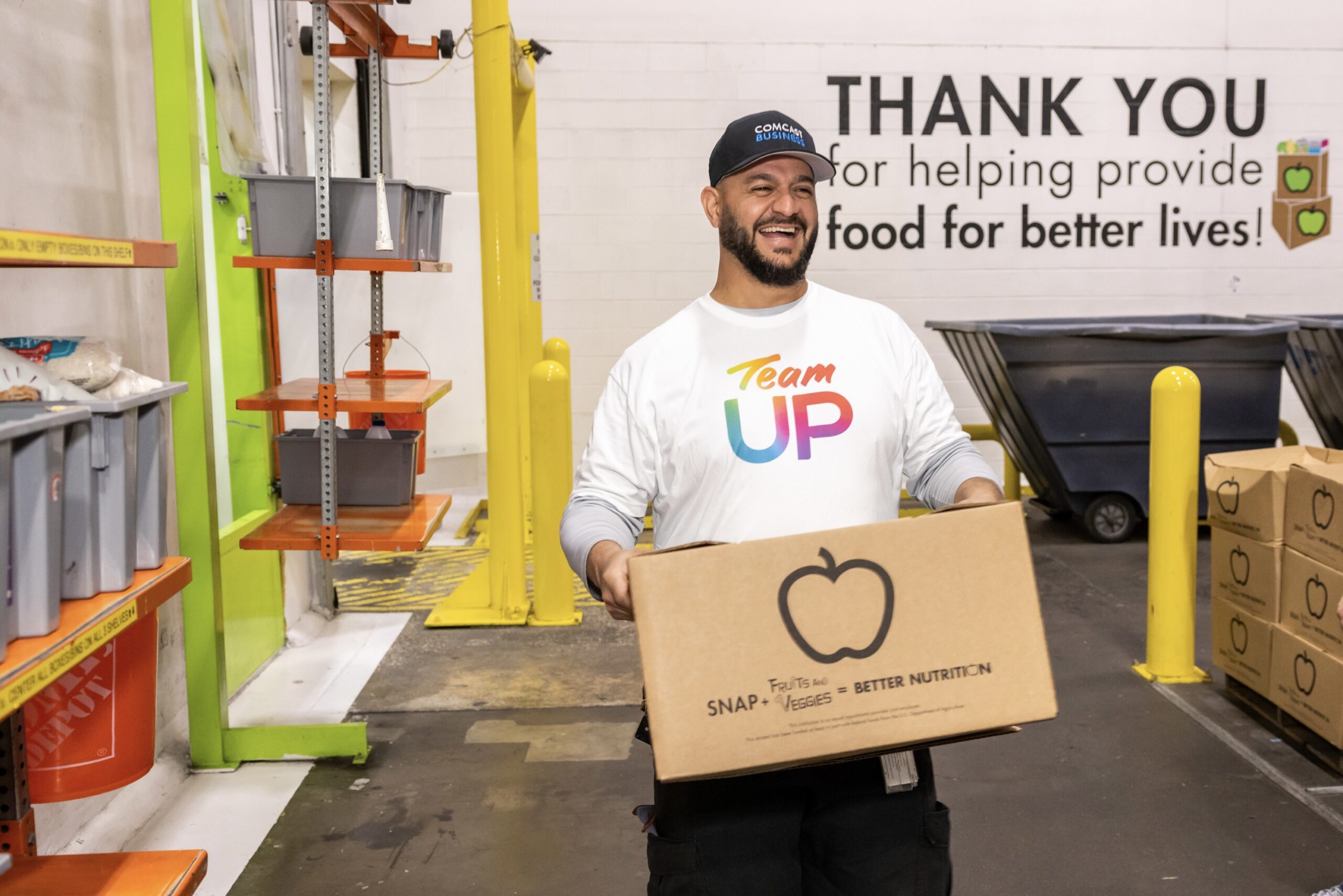 An employee with Comcast smiles as he helps packs boxes at the Houston Food Bank.