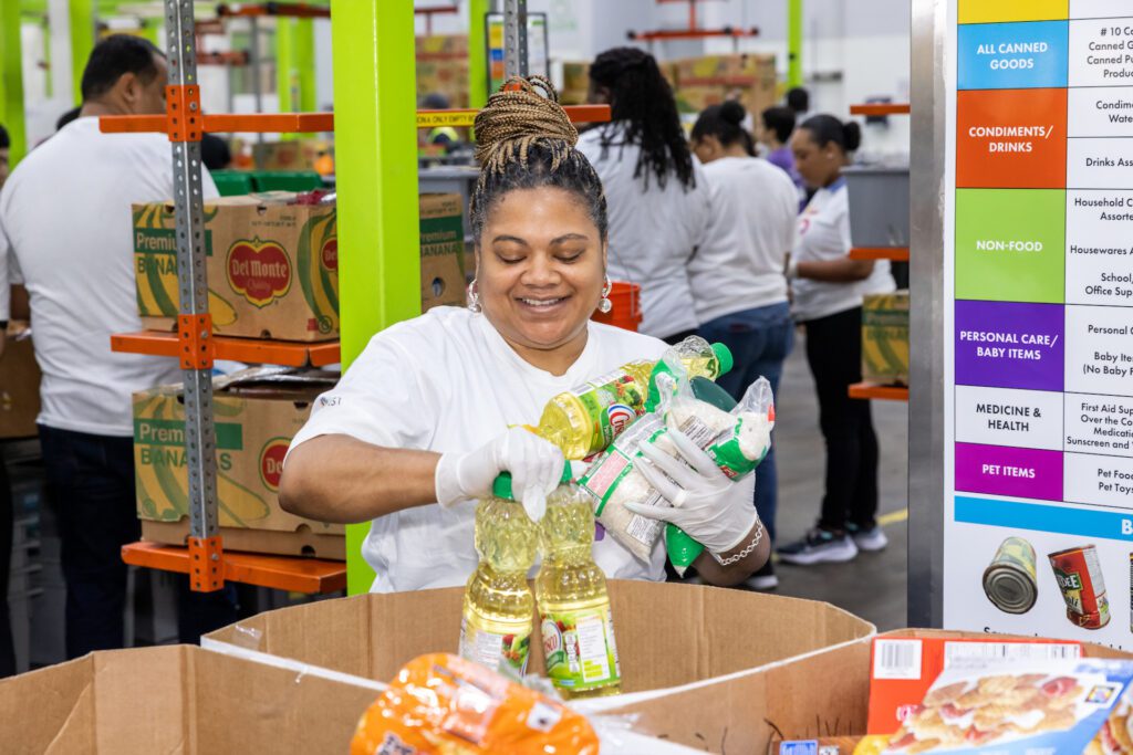 Volunteer carrying multiple bottles of cooking oil at food bank.