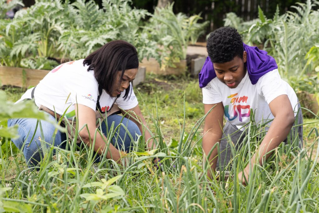 Two volunteers bend low and working in the garden