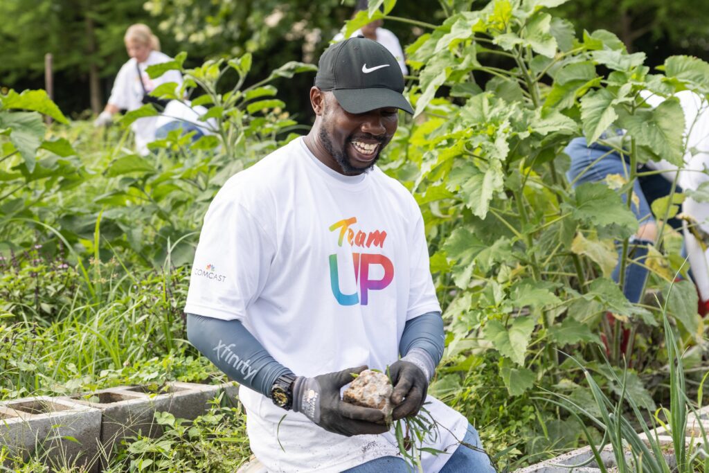 Smiling man wearing black cap and holding newly pulled weeds