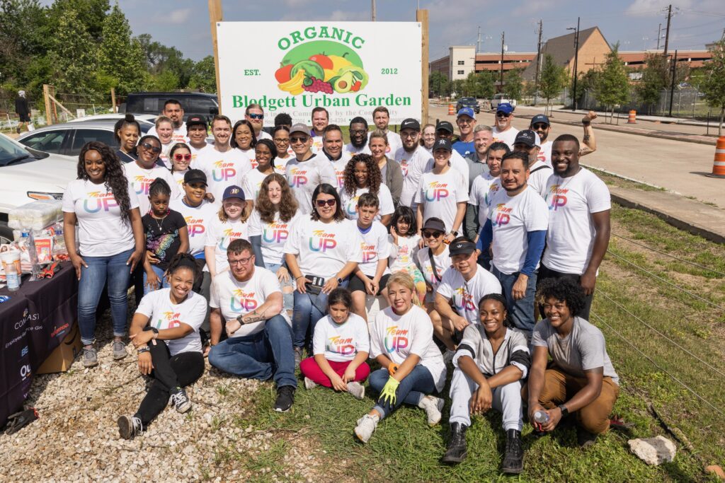 Large group of Team Up volunteers posing for picture in front of farm sign