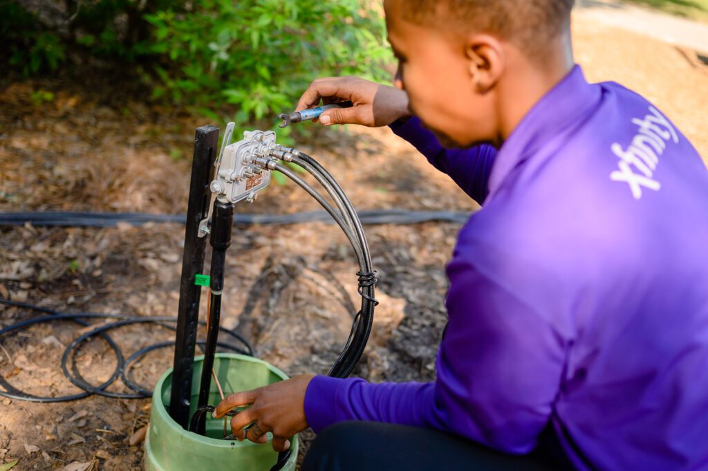 A technician bending down to check wires.