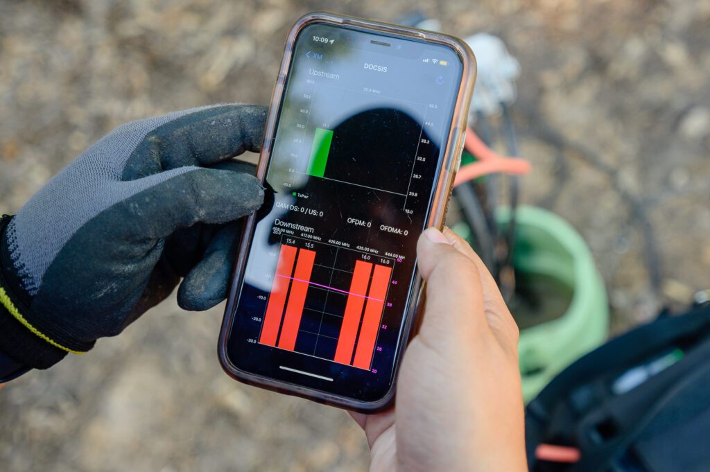 Up close of the hands of a technician holding cell phone to check signal levels.